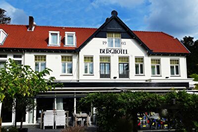 Amrâth Berghotel Amersfoort, historic hotel with red roof tiles and green surroundings.