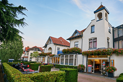 Amrâth Hotel Media Park in Hilversum, bright facade with colorful flowers and outdoor seating.